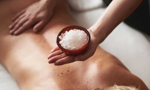 Person får kroppsmassasje med saltkrystaller for avslapning og velvære på spa.