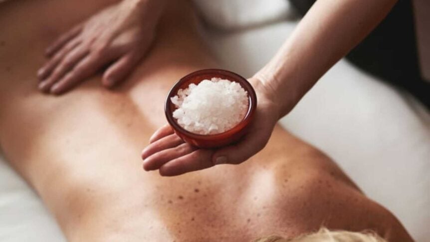 Person får kroppsmassasje med saltkrystaller for avslapning og velvære på spa.