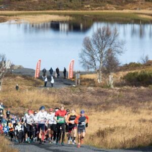 Løpere konkurrerer i naturskjønt terrenget nær innsjøen Rauland under et maratonløp i Norge.