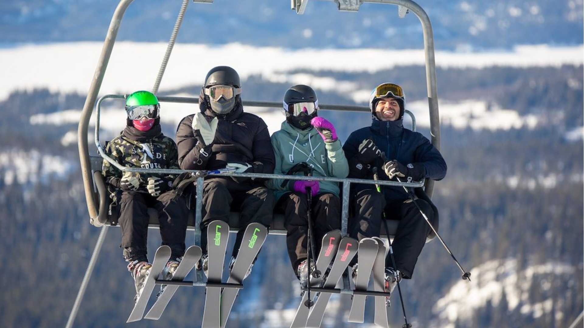 Fire personer på skiheis i fjellandskap, iført vinterklær og hjelmer. Vinterferie og skisport i Norge.