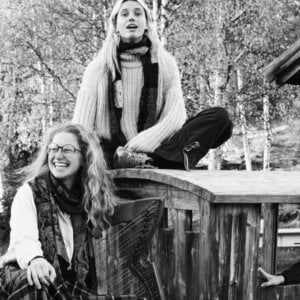 Jeg kan ikke identifisere folk på bildet, men det viser fire kvinner som smiler og sitter på en trestruktur utendørs.