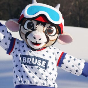 Maskot i vintertøy med Bruse på genseren i snølandskap.