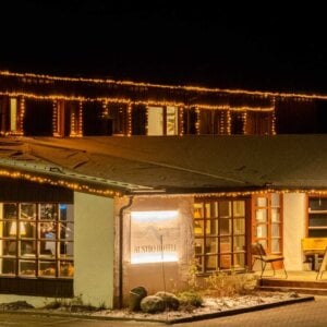 Utsmykket hotell inngang med julelys om natten på Rauland, skiltet Austbø Hotell og Raualand Feriesenter kan sees.