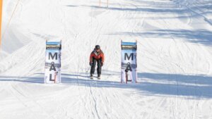 Person på ski når målstreken i solfylt vinterlandskap.