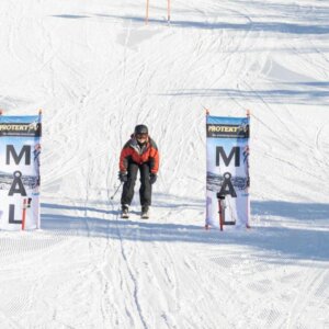 Person på ski når målstreken i solfylt vinterlandskap.