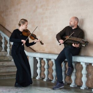 To musikere spiller fiolin og nøkkelharpe på en trapp med balustrade.