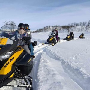 Ski-doo event i snøen med gruppen som kjører snøskuter i vakker vinterlandskap.
