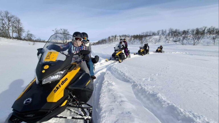 Ski-doo event i snøen med gruppen som kjører snøskuter i vakker vinterlandskap.