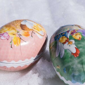 Fargerike påskeegg med kyllinger, ligger på snø. Perfekt for påskefeiring og dekorasjon.