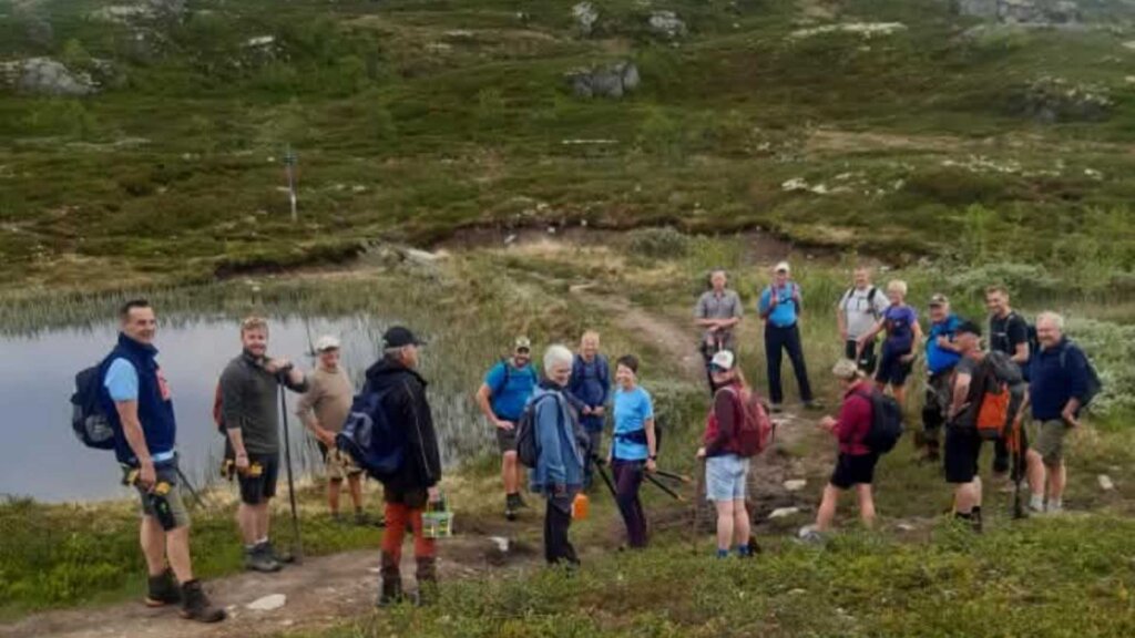 Folk samles ved en innsjø under en fottur i naturskjønne omgivelser, klare for en spennende opplevelse.