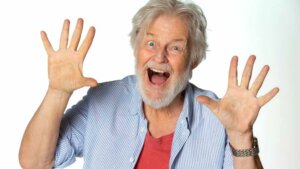 Old man with gray hair, smiling and holding his hands up showing enthusiasm and joy.